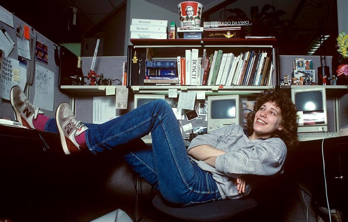 A woman in sneakers leaning back in an office chair