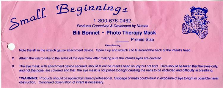 A pink piece of paper, about 8.5 inches wide and 3.25 inches high, with instructions for placing the mask over a baby’s head and eyes. An illustration of a teddy bear is in the upper right corner.Text includes: Small Beginnings . . . Products conceived and developed by nurses. . . . “Warning: Products should be applied by trained professional. Slippage of mask could result in exposure of eye to light or possible nasal obstruction. Continued observation of infant is necessary.” 