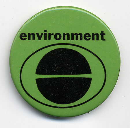 Green metal button with “environment” in black letters above the Earth Day logo