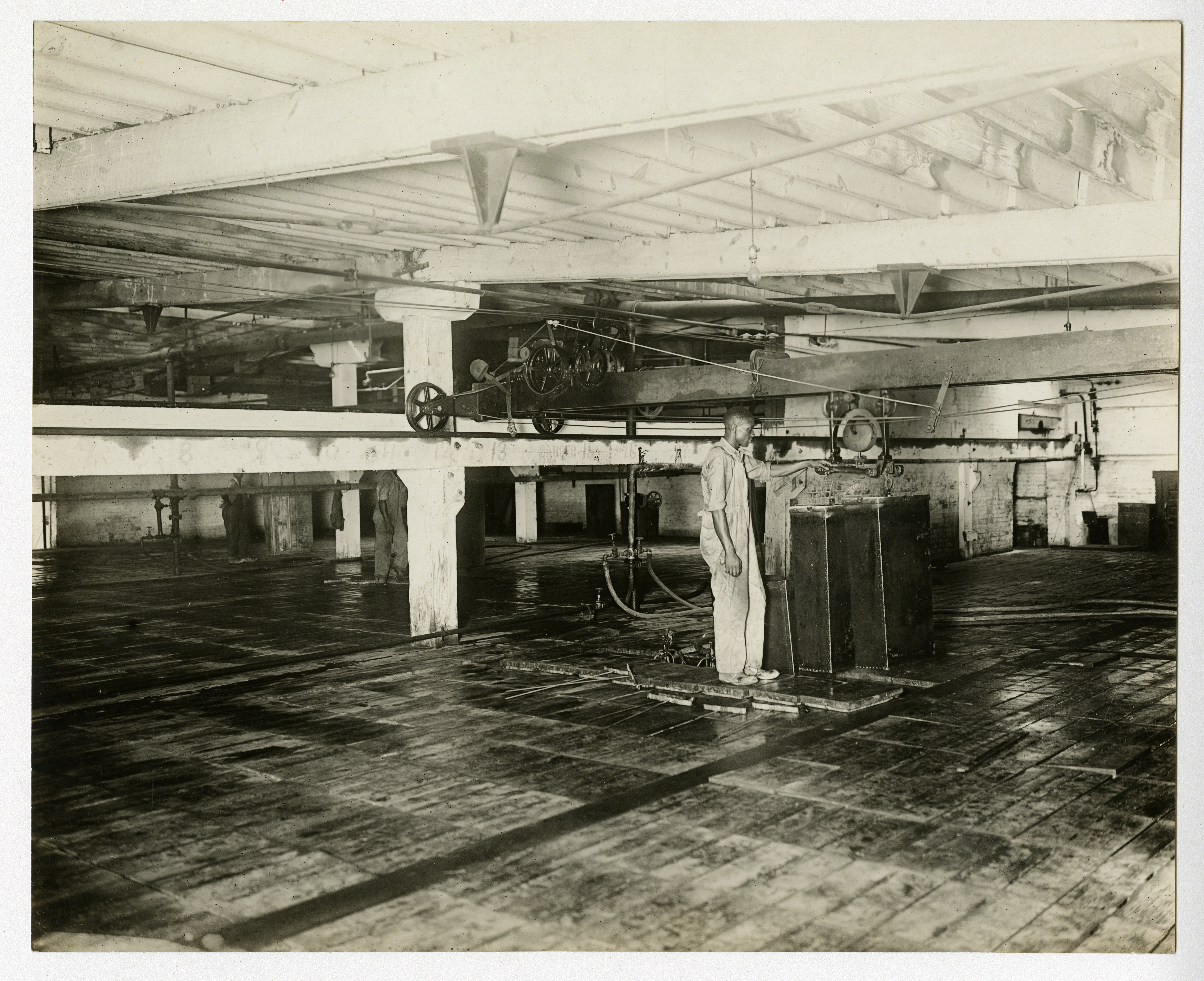  A worker operates the can hoist on the floor of a Frick-built ice plant, undated (AC0293-0000012).