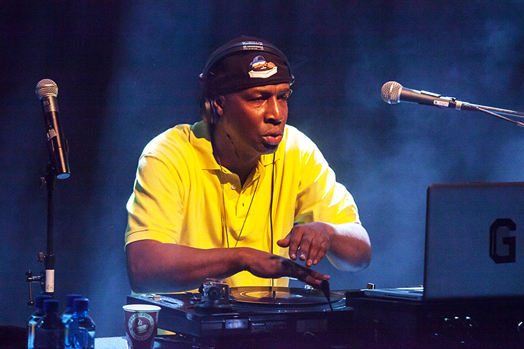 Hip hop legend Grandmaster Flash in a yellow tee shirt and backwards baseball cap, working a turntable