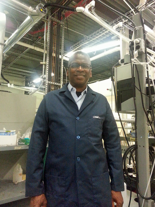 Lonnie Johnson, wearing a blue lab coat, standing in a lab