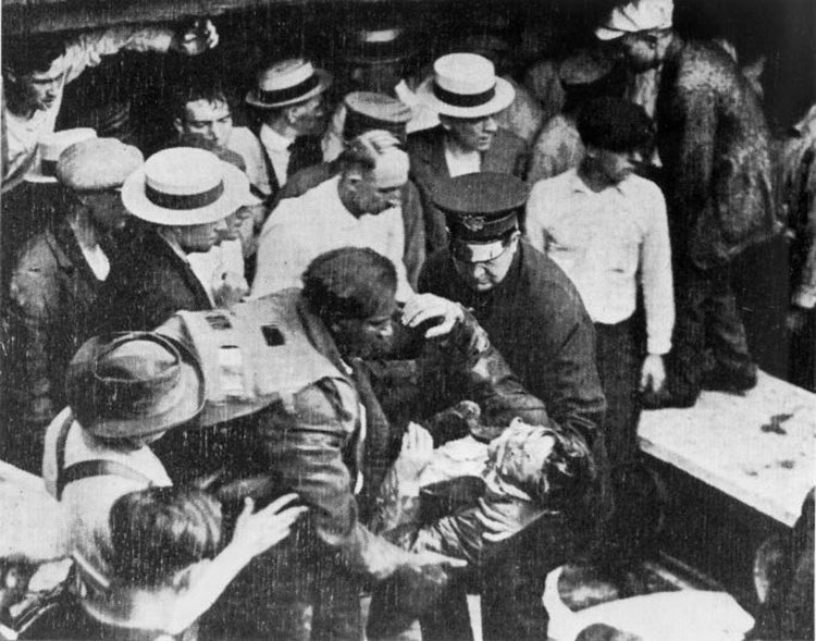 Morgan pulls a man out of a tunnel while surrounded by a large crowd