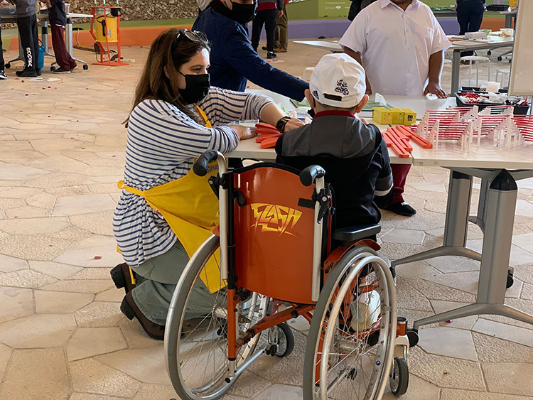 A young child in a wheelchair works with a Spark!Lab facilitator on a stadium-building activity.