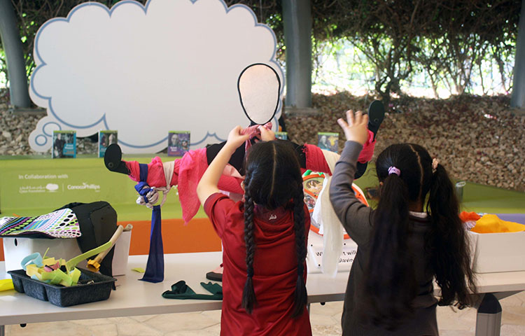 Two young girls work at creating a piece of sports attire on a cut-out mannequin.