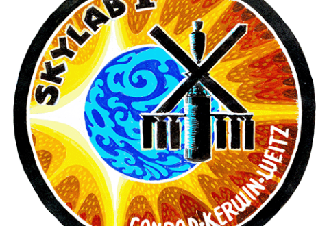 The Skylab 1 patch is a circle shape with a swirly-blue circle in the center to represent Earth, a bright orange gradient in the background represents the sun, and an artist's depiction of skylab is off-center. The words "Skylab 1" and "Conrad, Kerwin, Weitz" are inscribed on the inside edges of the circle.