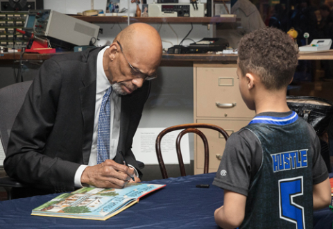 Kareem Abdul-Jabbar signing his book for a young boy