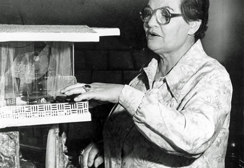 Frances Gabe pointing to model of her self-cleaning house, 1979