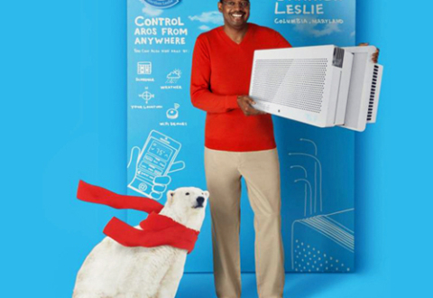 Advertising image showing inventor Garthen Leslie holding the Aros air conditioner that he invented. He stands against a backdrop of blueprint-type sketches for the air conditioner. A cut-out of a polar bear wearing a red scarf is at his feet.