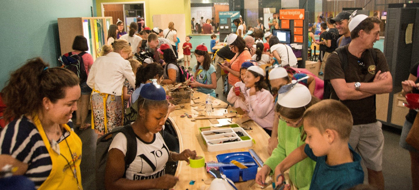 A very crowded overview of Spark!Lab, taken from the rear of the room and looking towards the entrance. This photo was taken on opening day, July 1, 2015, and visitors are wearing the propeller beanies that they received as gifts from the museum.