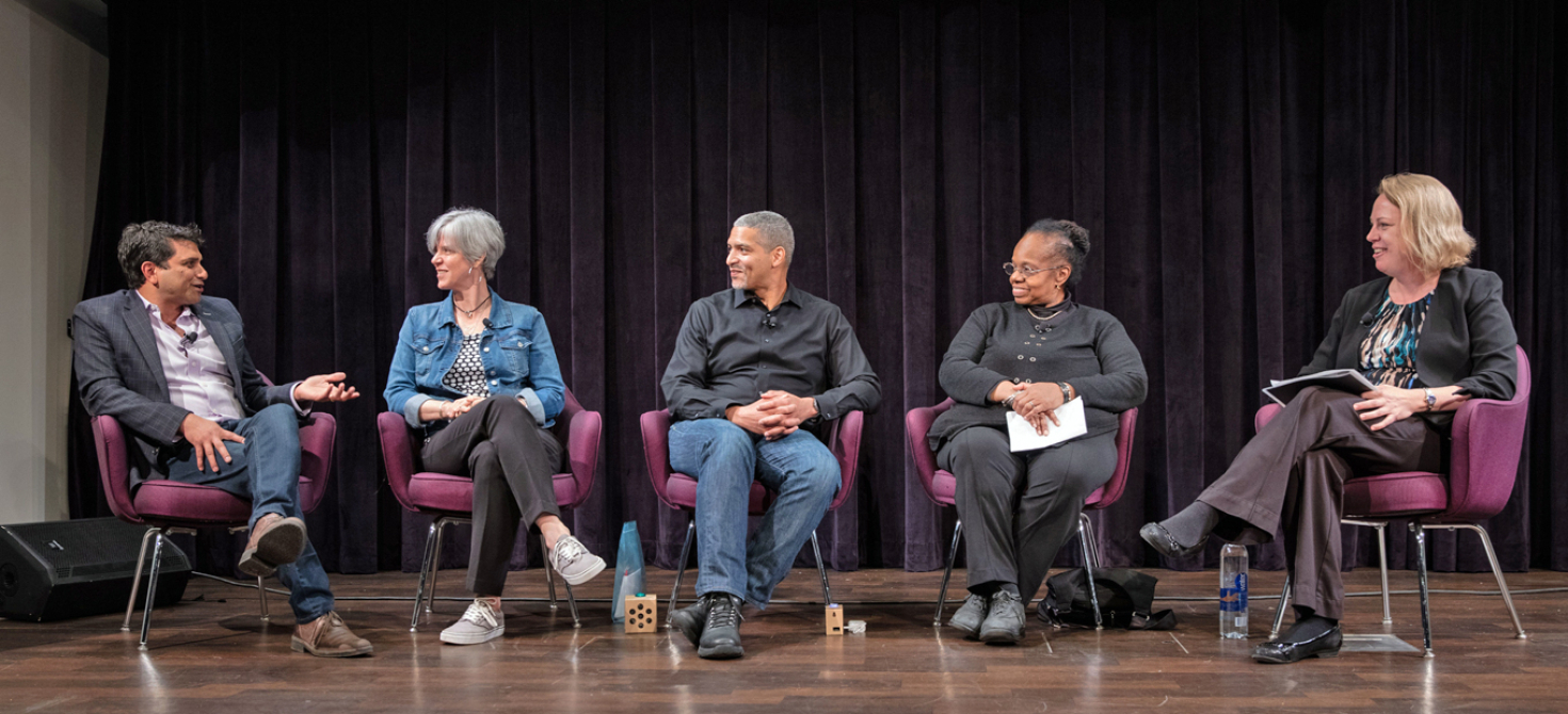 Panelists in chairs on stage