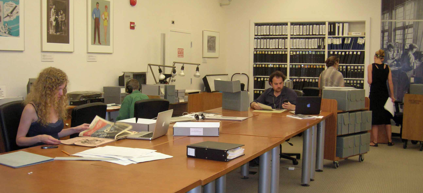 Archives Center reading room with large tables and people doing research. Lemelson Fellow Hallie Lieberman sits at the far left and fellow Matthew Hockenberry sits at the center of the photo.