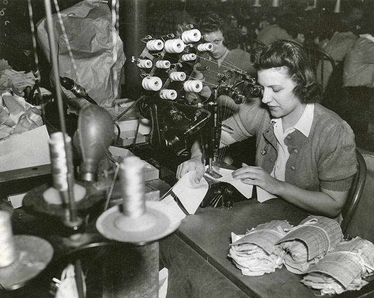 Woman working at sewing machine that has several bobbins of thread