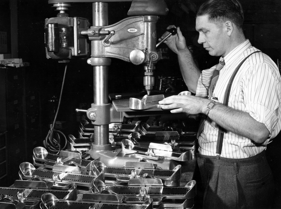 A worker using a drill press at the Brannock Device Company