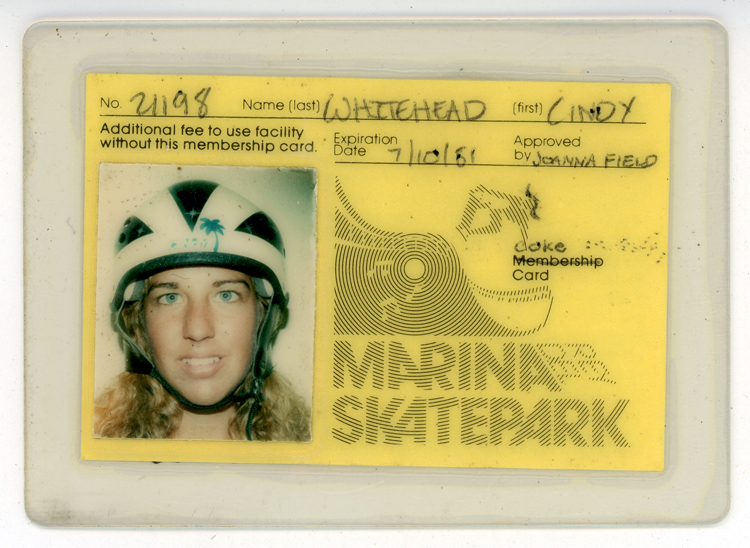 Laminated identification card for Marina Del Rey Skatepark, with a yellow background, No. 21198, Cindy Whitehead’s name, and expiration date of 10 July 1981. A headshot of Whitehead wearing a helmet is on the left of the card; on the right is the name of the park depicted with curving lines suggesting a skate ramp. The word “membership” has been crossed out and replaced with the handwritten word “coke.”