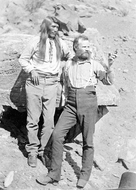 Tau-Gu standing with the John Wesley Powell on rocky soil