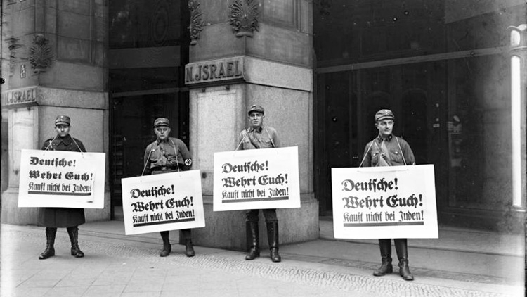 4 Nazi storm troopers holding large signs outside a department store