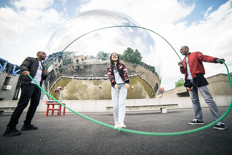 2 men turning the double Dutch ropes while a woman jumps