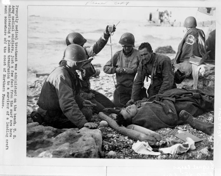 Army medics attending to a wounded soldier on a beach