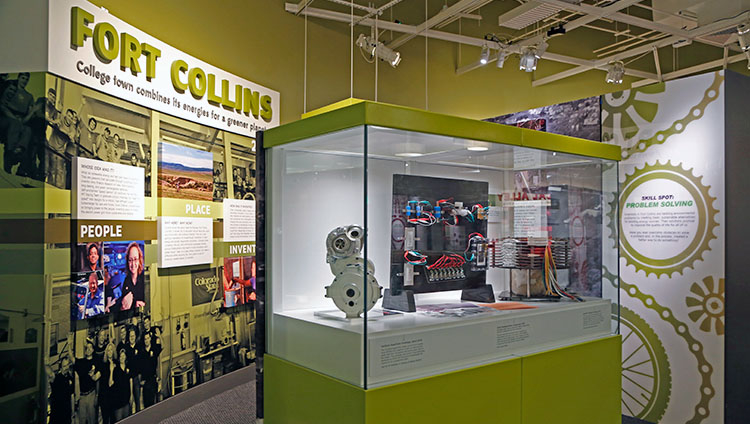 Looking into the Fort Collins section of the exhibition, with several prototypes displayed in a case at the entrance.