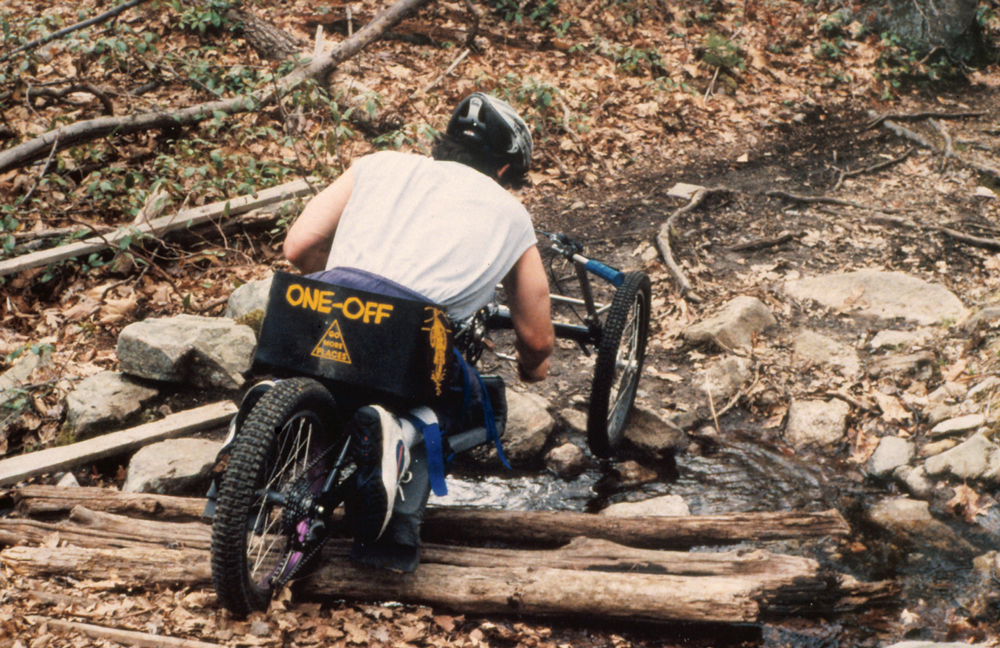 Image of cyclist going downhill on a handcycle. 