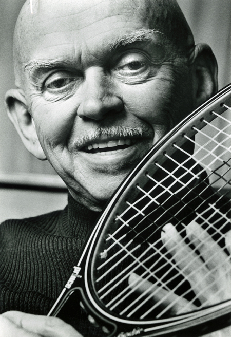 Head holding a Prince tennis racket near his face.