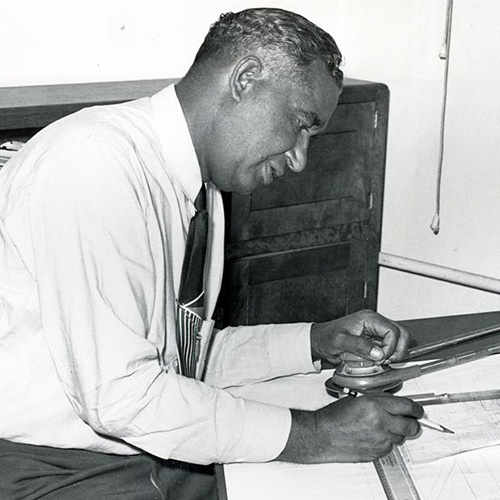 Frederick McKinley Jones working with a pencil and mechanical drawing at his drafting table, undated.