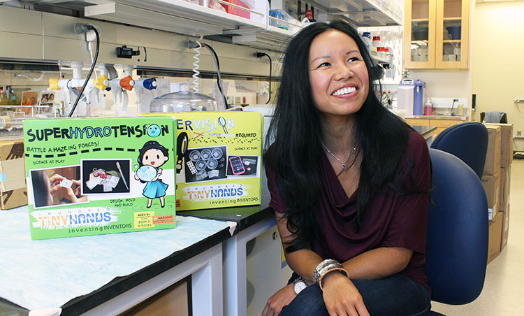 Khine sitting next to a table with an educational toy box next to her