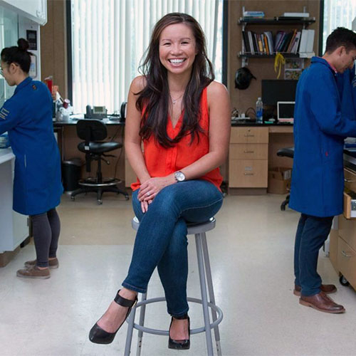 Khine sitting on a metal stool in her lab