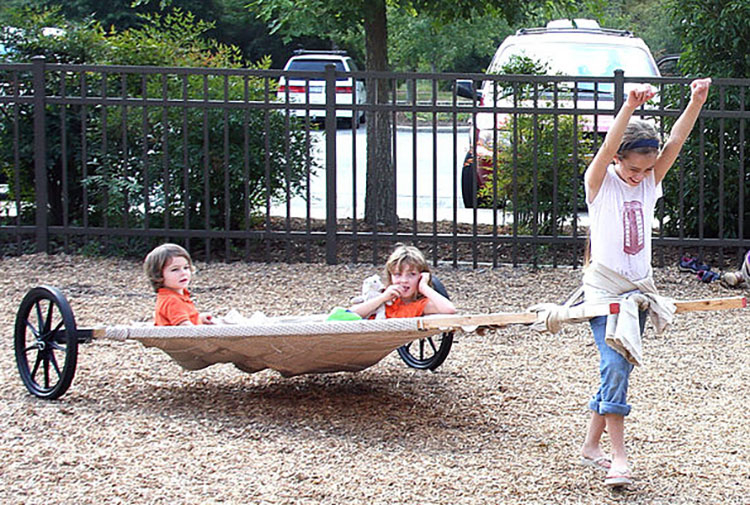 Two small children riding in the travois while a third child pulls it.