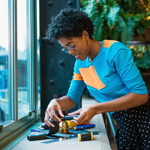 Maxey bent over a workbench using tools