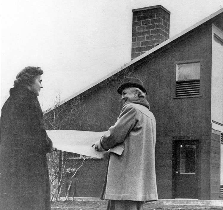 Telkes and architect Raymond looking at plans outside solar house