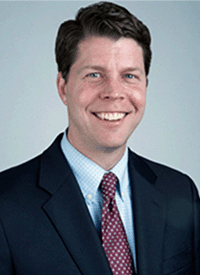 Professional headshot of a white man with short brown hair.