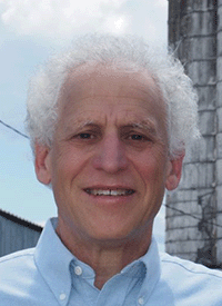 A professional headshot of a white man with white hair.