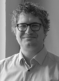 Professional headshot of a white man with glasses.