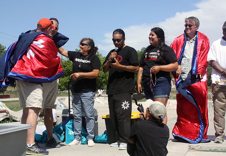 3 Smithsonian staff wrapped in star quilts presented by 3 members of Lakota nation