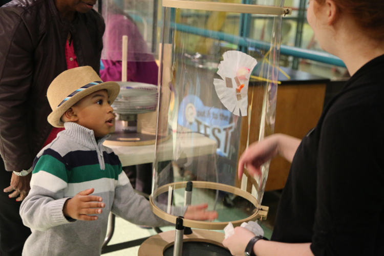 A young boy tests his prototype in the wind tunnel in SparkLab at the Michigan Science Center