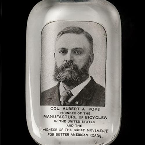 A glass paperweight featuring Albert A. Pope (1843-1909), Hartford bicycle manufacturer and leader of the American “good roads” movement, about 1890s