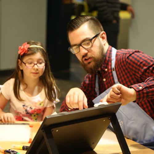 A facilitator works with a young girl on a Spark!Lab invention activity (Michigan Science Center) 